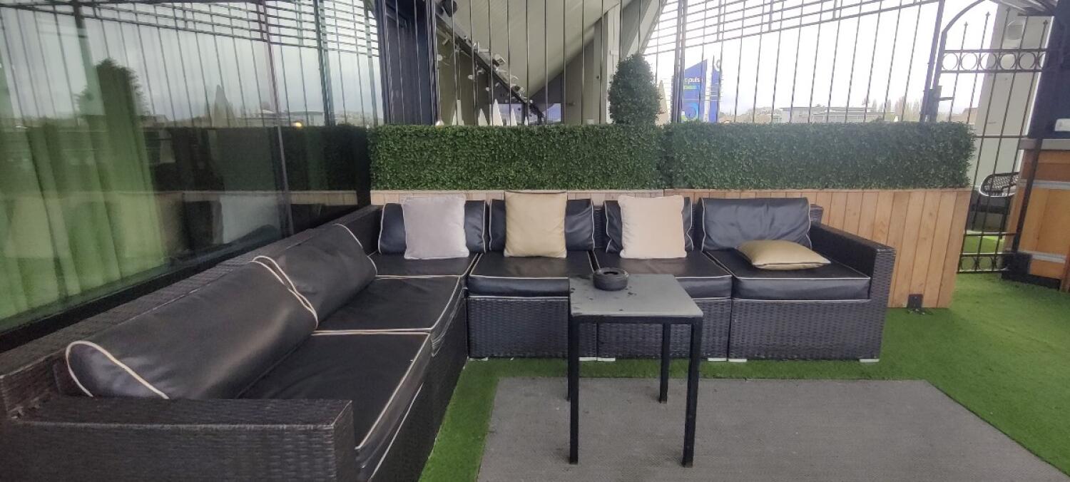From blue-framed door facing left. Couch along left and back. Table in centre.