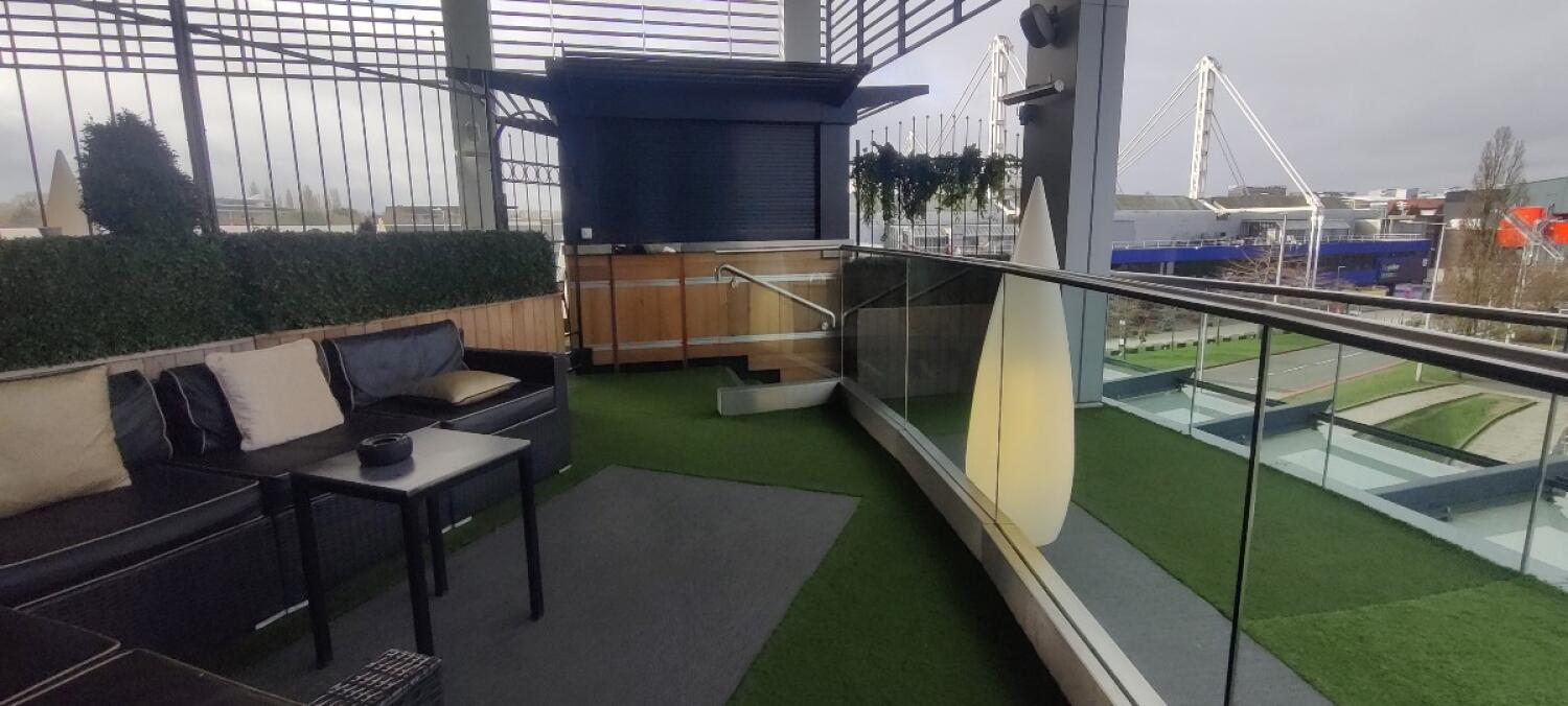 From blue-framed door facing straight. Couch and table along left. Path to balcony on right.