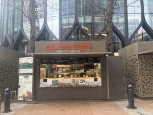 Open archway ahead. Counter with food display ahead. Menu board above.