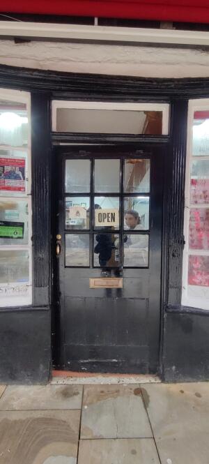 Black wood-framed glass door ahead. Push from handle on left to open.
