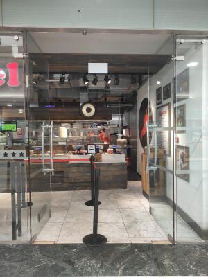 From mall corridor facing venue. Double glass doors ahead. Push from metal handles at centre to open.