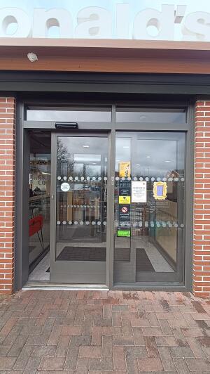 Grey metal-framed glass door sliding from left. Enter through left.