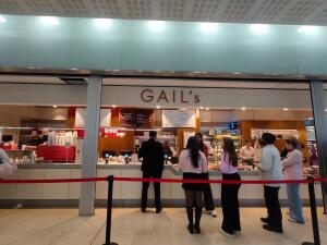 From mall pathway facing venue. Queue cord along front. Till counters behind.