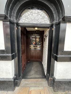 White wooden door with handle on left. Push to open.