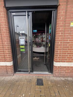 Black metal-framed glass doors. Push from metal handles at centre to open.