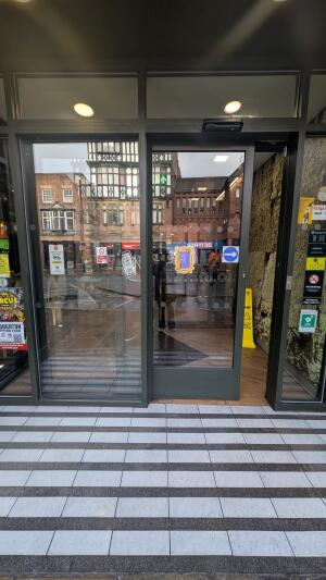 Dark metal-framed automatic glass door. Door slides left to open.