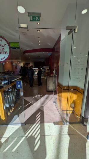 Glass door. Push handle on left to open. Doorbell for assistance on left.