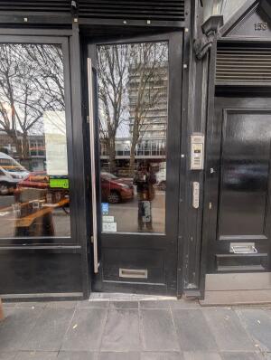 Black-framed glass door. Push from vertical handle on left to open.