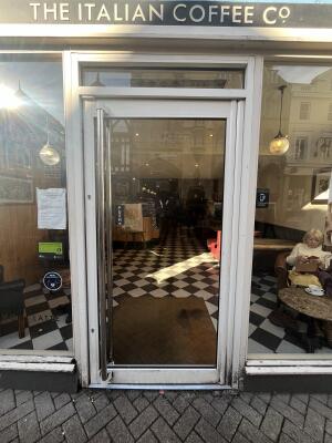 White metal-framed glass door. Push from handle on left to open.