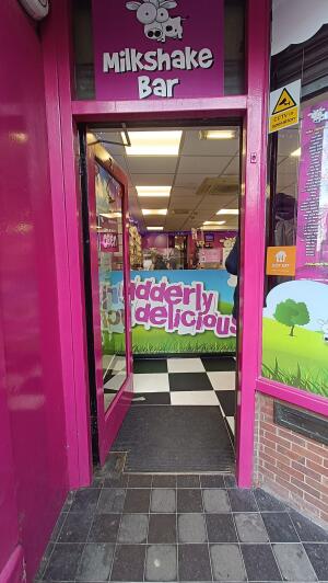 Pink-framed glass door to venue. Push from handle on right to open.