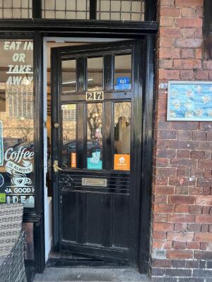 Black wooden door with glass panels. Push from handle on left to open.