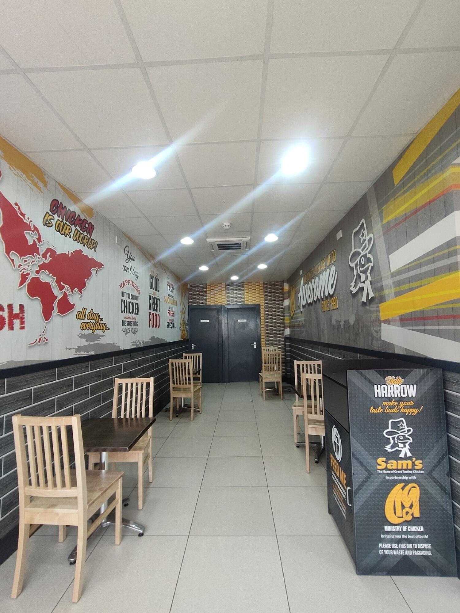 From archway entrance facing right. Tables and chairs along left and right walls. Black bin at front right.