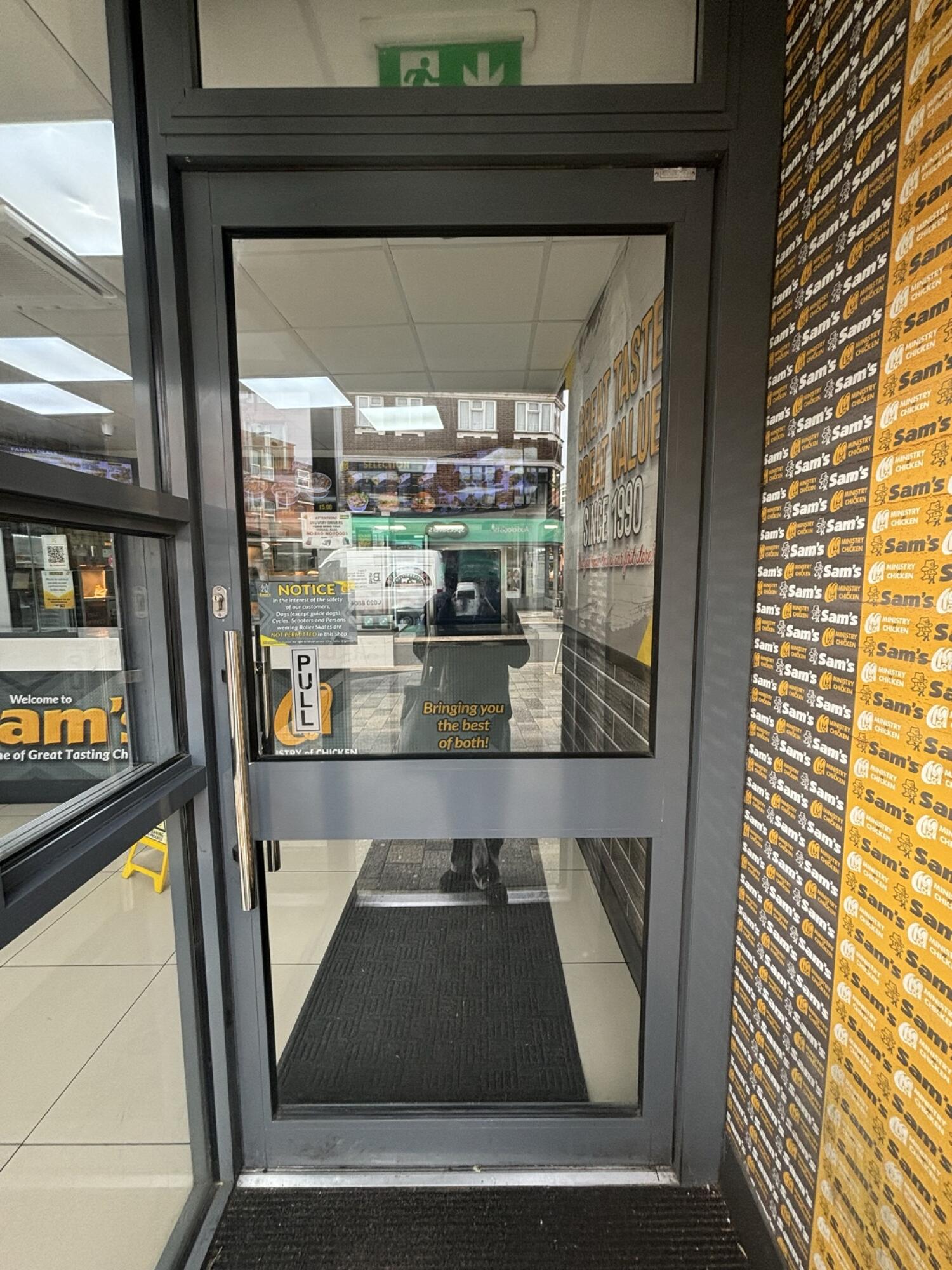 From archway facing straight. Grey metal-framed glass door ahead. Pull from metal handle on left to open.
