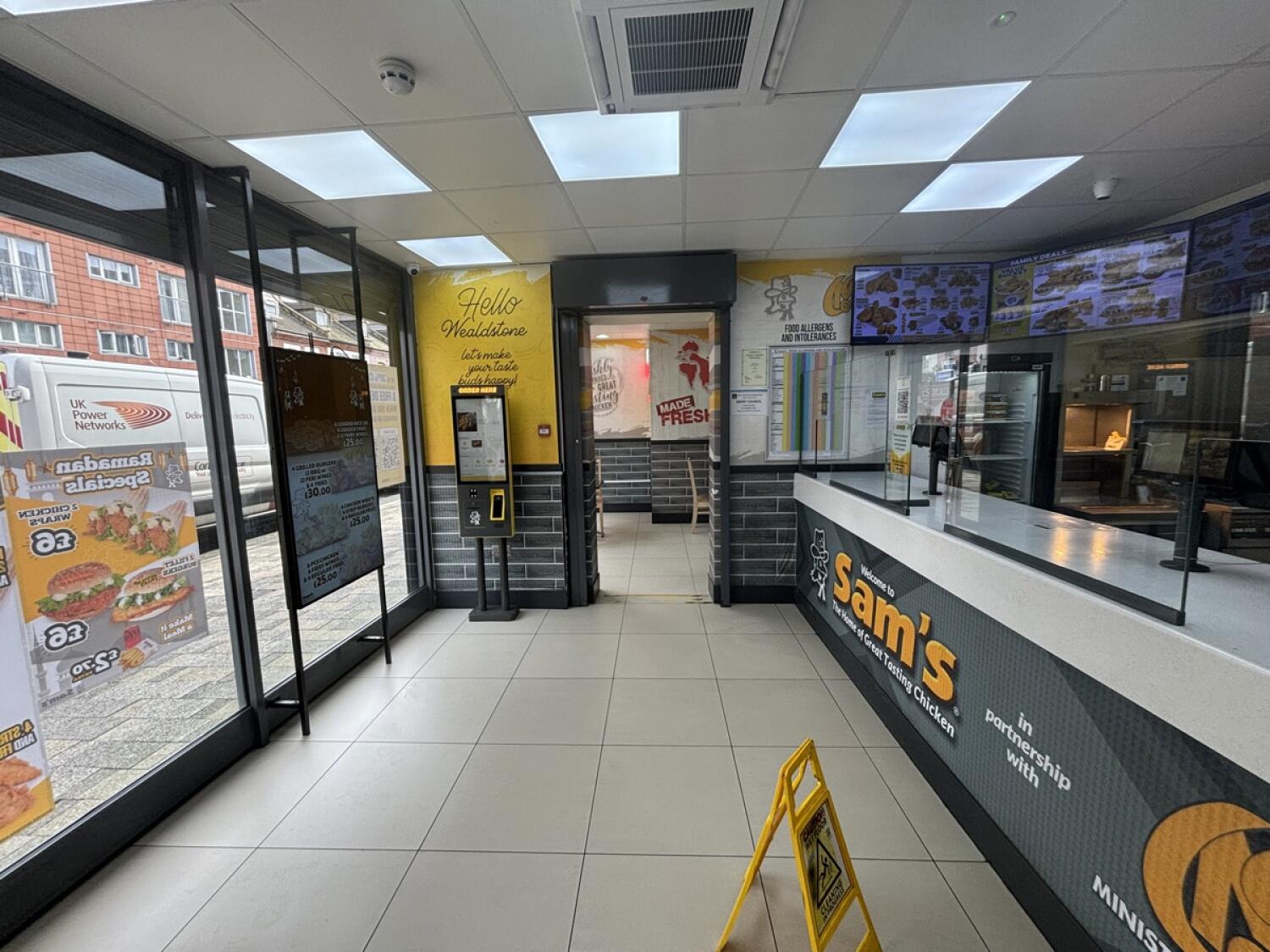 From entrance facing left. Counter along right. Path ahead to side space. Kiosk at back left.