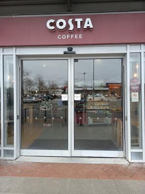 Glass automatic sliding doors with silver frame ahead. Doors slide to left and right to open.