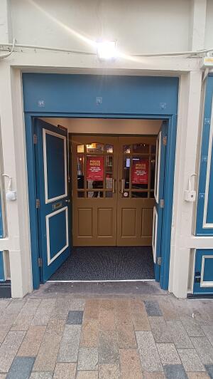 Blue wooden doors to venue. Push from handles at centre to open.