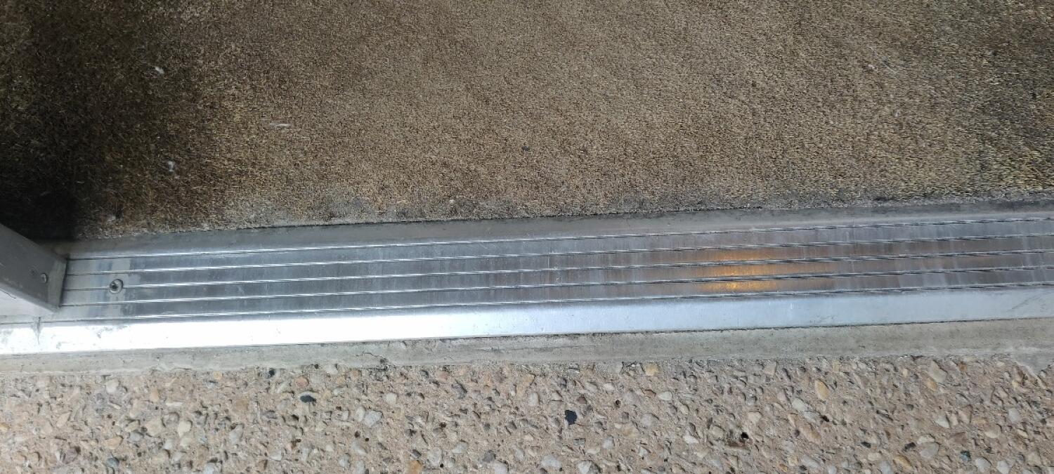 Small bump at foot of door. Doormat immediately after threshold.