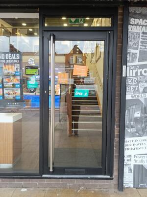 Black metal-framed glass door ahead. Push from vertical handle on left to open.