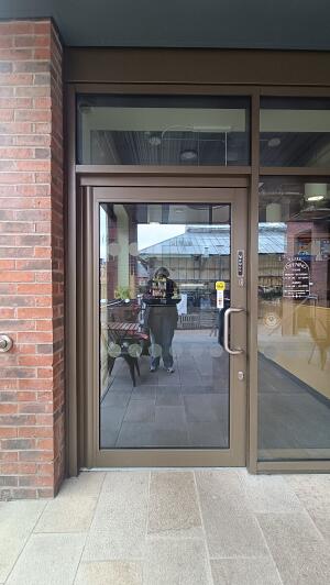 Olive coloured metal-framed glass door to venue. Pull from metal handle on right to open.