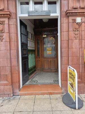 Black wooden doors with glass panel ahead. Push from centre to open.