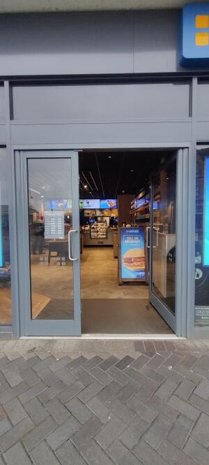 Grey metal-framed glass doors ahead. Push from metal handles at centre to open.
