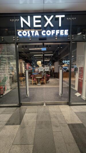 Glass doors with metal frame. Automatic doors slide open from centre.
