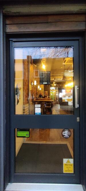Dark metal-framed glass door ahead. Push from handle on right to open.