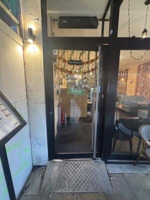 Black metal-framed glass door ahead. Push from vertical handle on right to open.