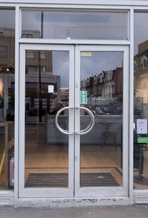 Grey metal-framed glass doors ahead. Push from metal handles at centre to open.