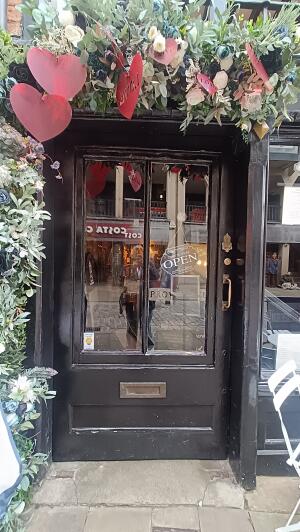 Black wood-framed glass door to venue. Push from handle on right to open.