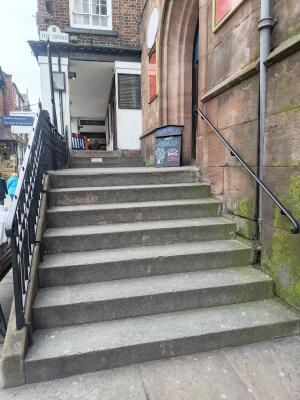 From street facing venue. Staircase ahead, leading up. Handrails along left and right.