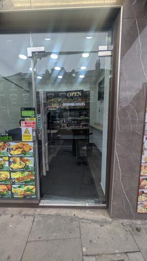 Glass door with metal frame. Push from handle on left to open.