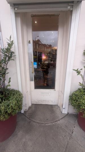White wood-framed glass door. Push from metal handle on left to open.