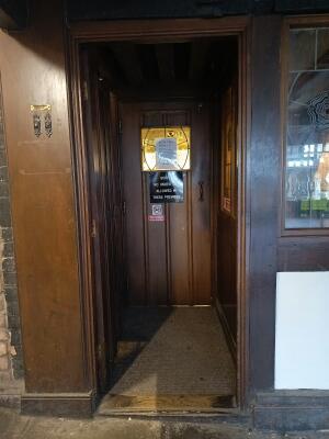 Brown wooden door ahead. Push from handle on right to open.