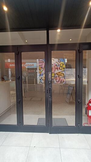 Black metal-framed glass doors to venue. Pull from handle at centre to open.