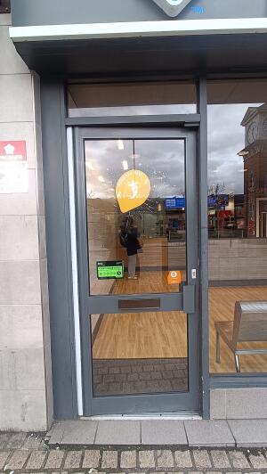 Grey metal-framed glass door to venue. Push from handle on right to open.