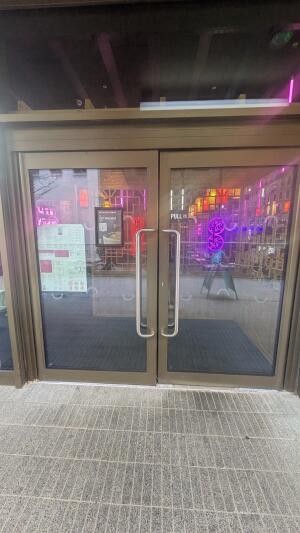 Bronze metal-framed glass doors. Pull from handles at centre to open.