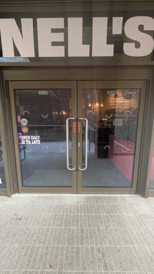 Brown metal-framed glass doors. Pull from metal handles at centre to open.