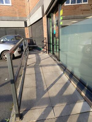 From street facing venue. Built in ramp up to door. Handrails along left. Wall along right.