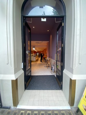 Double glass door, with black doorframe. Gold handles at centre. Push to open.