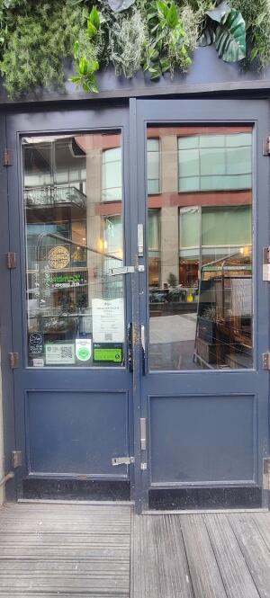 Dark blue metal-framed glass doors. Pull from handles at centre to open.