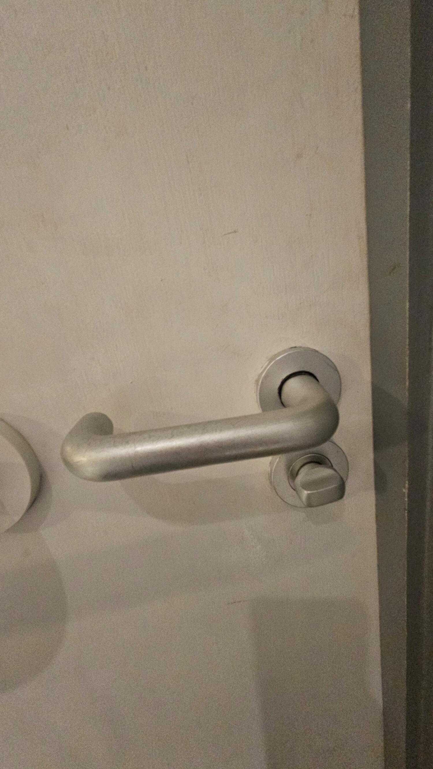 Silver metal door handle on white door. Push from handle on right to open.