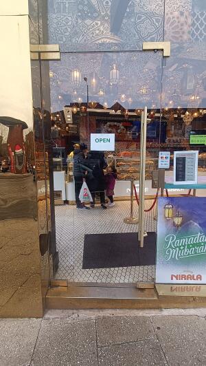 Glass door with gold metal frame to venue. Push from handle on right to open.