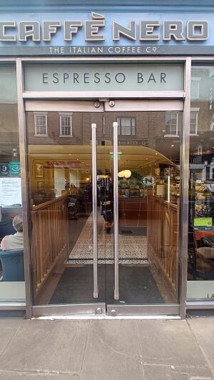 Glass doors to venue. Vertical metal handles on centre. Push handle at centre to open.