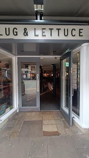 Grey metal-framed glass doors to venue. Pull from handles at centre to open.