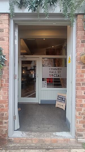 White wood-panelled door to venue. Push handle on right to open.