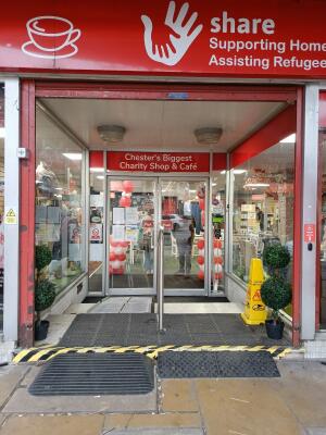Glass doors with metal handles at centre. Push from handles to open. Ramp at foot of doors.