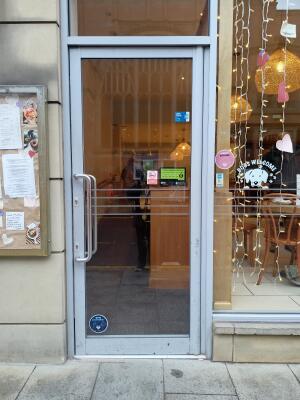 Silver metal-framed glass door ahead. Push from handle on left to open.