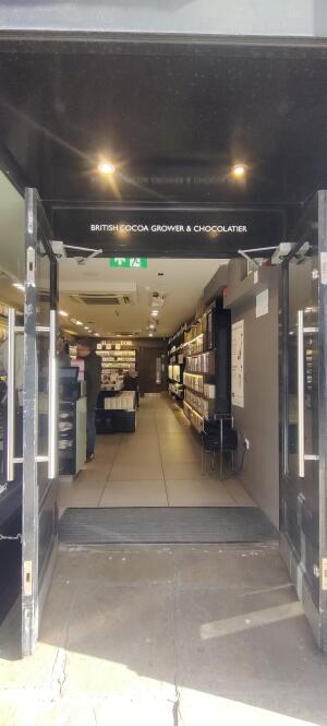 Black metal-framed glass doors. Push from metal handles at centre to open.