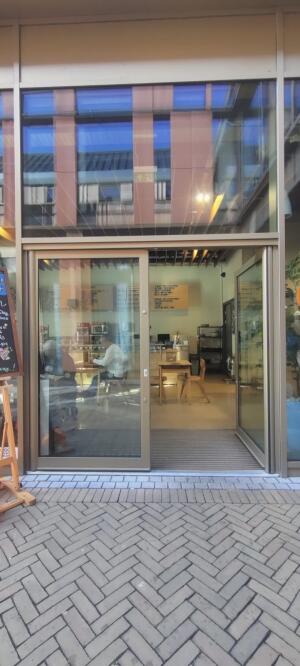 Beige metal-framed glass door. Push metal strip at centre to open.